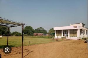 a building in a field next to a dirt road at Ranthambore Bagh niwas in Sawāi Mādhopur