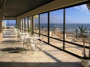 a balcony with tables and chairs and a view of the ocean at Tubarinho Apartment in Costa da Caparica