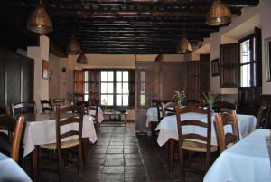 a restaurant with white tables and chairs and windows at Hotel Rural San Roque in Pitres