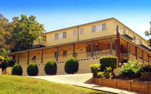 a large yellow building with balconies and bushes at Riverview Boutique Motel in Nambucca Heads