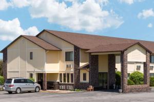 a building with a car parked in a parking lot at Super 8 by Wyndham Perry IA in Perry