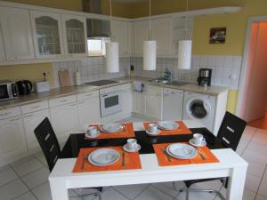 a kitchen with a white table with chairs and a washing machine at Apartment Erfordia Erfurt am Egapark in Erfurt