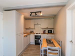 a kitchen with white cabinets and a wooden table at Ivy in Filey