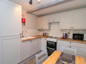 a kitchen with white cabinets and a stove top oven at Ivy in Filey