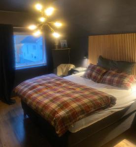 a bedroom with a bed with a plaid blanket and a window at Flott beliggenhet svært sentralt i sentrum in Svolvær