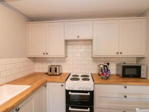 a kitchen with white cabinets and a stove top oven at Ivy in Filey