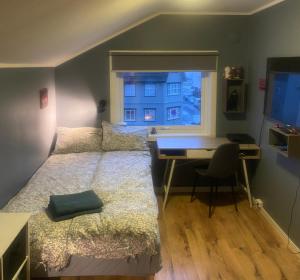 a bedroom with a bed and a desk and a window at Flott beliggenhet svært sentralt i sentrum in Svolvær