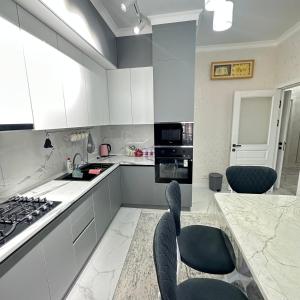 una cucina con mobili bianchi, tavolo e sedie di КАРАВАН САРАЙ 15 дом a Türkistan