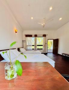 a bedroom with two beds and a table with a plant at Raa Pala Lake Resort in Anuradhapura