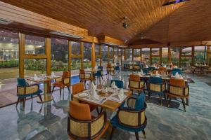a restaurant with tables and chairs and windows at Regenta Resort Sakleshpur in Sakleshpur