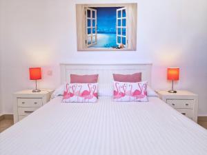 ein Schlafzimmer mit einem weißen Bett mit rosa Flamingos-Kissen in der Unterkunft La Graciosa Punta Caracol in Caleta de Sebo