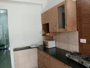 a kitchen with a black counter top and a microwave at 3BHK Luxury Apartment- LOTUS INN in Gurgaon