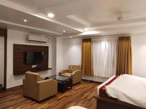 a hotel room with a bed and a tv at Hotel Vaishnavi Grand in Warangal