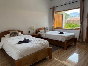 two beds in a room with a window at Amanda Boutique in Nongkhiaw