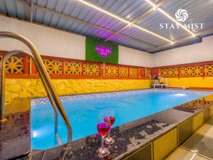 a swimming pool with two wine glasses on a counter at Staymist - Casa Palais in Lonavala