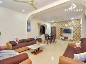 a living room with brown couches and a table at Staymist - Casa Palais in Lonavala