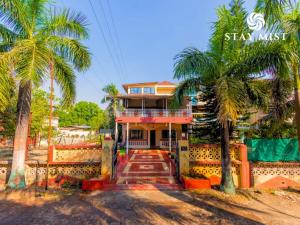 a house with palm trees in front of it at Staymist - Casa Palais in Lonavala