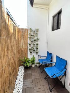two blue chairs on a patio with plants at Cozy Escape Calaca in Calaca