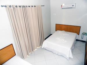a bed room with a white bedspread and a white curtain at Itaparica Praia Hotel in Vila Velha
