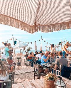 a group of people sitting at tables on the beach at Beleef Noordwijk strandhuisje in Noordwijk aan Zee +27 photos