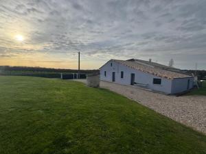 a white building in a field with a grass field at maison à la campagne in Cleyrac