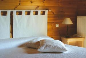 a bedroom with a bed with a pillow and a lamp at Logis - Hôtel & restaurant Les Trois Fontaines in Marconne