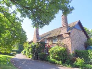 a brick house with two chimneys on a street at Tudor Cottage in Bossington