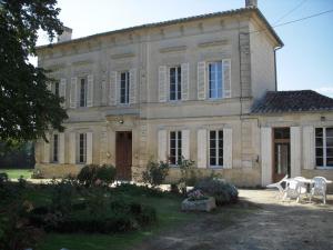 una grande casa in pietra con sedie di fronte di La Maison des Aurélines a Puisseguin