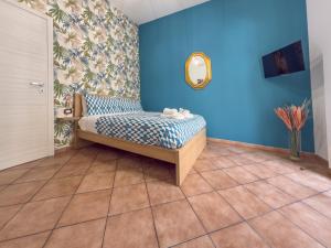 een slaapkamer met blauwe muren en een bed met een spiegel bij Sabbie dell'Etna - Eleganza e Comfort nel Cuore di Catania con Parcheggio Privato in Catania