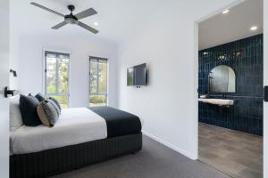 a bedroom with a bed and a bathroom with a mirror at Castlemaine Gardens Luxury Accessible Villa in Castlemaine