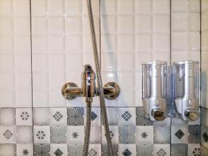 a shower in a bathroom with white tiles at Luxurious Studio at De Prima Apartment By Travelio in Medan +16 photos