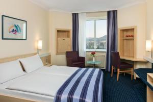 a hotel room with a bed, chair and a tv at IntercityHotel Freiburg in Freiburg im Breisgau