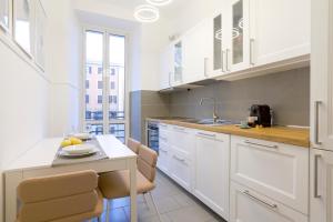 ローマにあるPiramide Deluxe Apartmentの白いキャビネットとテーブルと椅子のあるキッチン