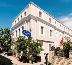 a white building with a blue sign in front of it at Bay Nihat Otel Lale in Ayvalık