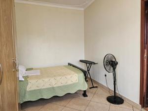 Habitación pequeña con cama y ventilador. en NL residence - Kampala, en Kampala