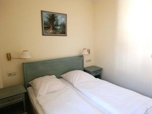 Bett in einem Zimmer mit zwei Nachttischen und einem Bild in der Unterkunft Fewo Rosenhof 13 in Kühlungsborn