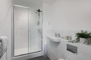 a white bathroom with a shower and a sink at Lovely Home Near Canal, Park, & Central MK in Milton Keynes +20 photos