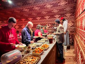 a group of people preparing food at a buffet at Wadi Rum Sky Tours & Camp in Wadi Rum
