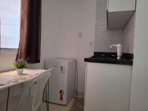 サルバドールにあるLinda Kitnet Mobiliada 06の冷蔵庫とテーブルのある小さなキッチン