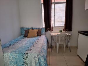 サルバドールにあるLinda Kitnet Mobiliada 06のベッドとテーブルと窓のある寝室