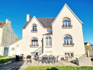 una casa bianca con tavoli e sedie di fronte di 731-Maison Bretonne a proximte des plages et des s a Plouhinec
