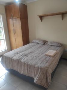 a bedroom with a bed and a wooden cabinet at Tumelos Place in Bloemfontein