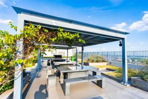 a pergola with benches and tables on a roof at Swimming Pool 35th Floor District 7 in Ho Chi Minh City