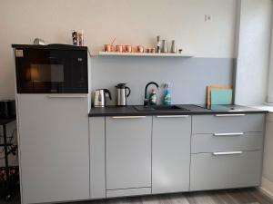 a kitchen with white cabinets and a black microwave at Luxus Appartement Motel Ambiente 2 in Bad Säckingen