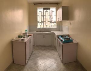 a kitchen with white cabinets and a sink and a window at Atlantis BNB in Nakuru