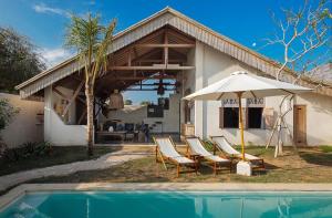 un gruppo di sedie e un ombrellone accanto a una casa di Beautiful Rustic 3bd Villa in Bingin a Uluwatu