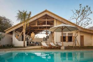 una casa con ombrellone, sedie e piscina di Beautiful Rustic 3bd Villa in Bingin a Uluwatu