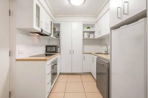 a white kitchen with white cabinets and a sink at Inner City Gem - Stunning Views in Cairns