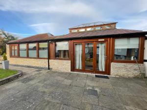a brick house with glass doors on a patio at Little Monks Suite in Offenham