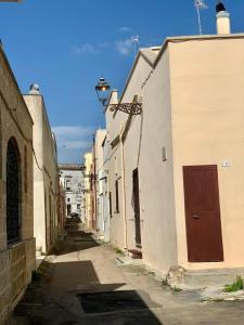 un callejón con edificios blancos y una puerta roja en Dimora Artus - Home Salento com, en Ugento